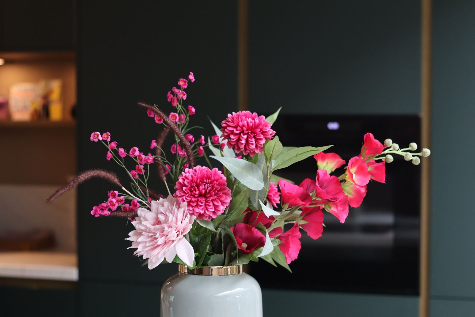 Roze boeket tegen donkergroene keukenkasten
